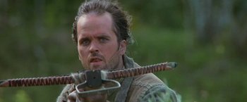 Movie still from “No Escape” (1994), directed by Martin Campbell – A person holding a sword; Close Up shot, Low angle