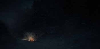 Movie still from “No Exit” (2022), directed by Damien Power – A car driving down a road at night with headlights on; Extreme Wide shot, High angle
