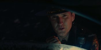 Movie still from “No Exit” (2022), directed by Damien Power – A man in a police uniform is looking at the camera; Close Up shot, Low angle
