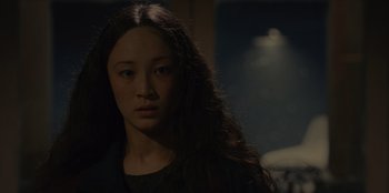 Movie still from “No Exit” (2022), directed by Damien Power – A woman with long black hair is looking at the camera; Close Up shot, Over the shoulder angle