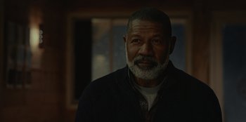 Movie still from “No Exit” (2022), directed by Damien Power – An older man with a gray beard is posing for a picture; Close Up shot, Over the shoulder angle