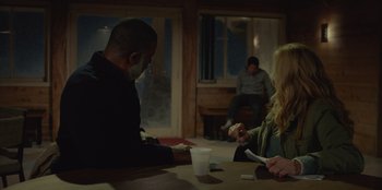 Movie still from “No Exit” (2022), directed by Damien Power – A group of people sitting at a table; Medium shot, Over the shoulder angle