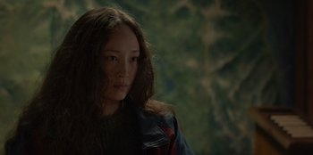 Movie still from “No Exit” (2022), directed by Damien Power – A woman with long brown hair wearing a blue jacket; Close Up shot, Over the shoulder angle