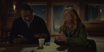 Movie still from “No Exit” (2022), directed by Damien Power – Two people sitting at a table with a cup of coffee; Medium shot, Over the shoulder angle