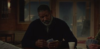 Movie still from “No Exit” (2022), directed by Damien Power – A man sitting at a table with a cup of coffee; Medium shot, Over the shoulder angle