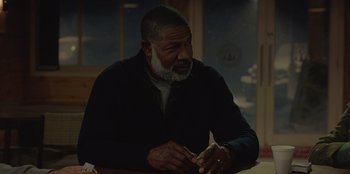 Movie still from “No Exit” (2022), directed by Damien Power – An older man sitting at a table with a sandwich in front of him; Close Up shot, Over the shoulder angle