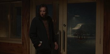 Movie still from “No Exit” (2022), directed by Damien Power – A man standing in front of a door; Medium shot, Low angle