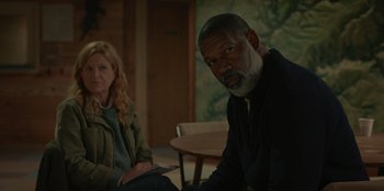 Movie still from “No Exit” (2022), directed by Damien Power – A man and a woman sitting next to each other in a room; Medium shot, Over the shoulder angle