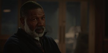 Movie still from “No Exit” (2022), directed by Damien Power – An older man with a gray beard looking into the distance; Close Up shot, Over the shoulder angle