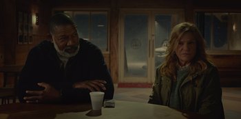 Movie still from “No Exit” (2022), directed by Damien Power – A man and a woman sitting at a table with a drink; Medium shot, Over the shoulder angle