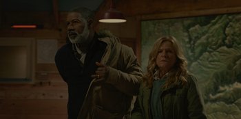 Movie still from “No Exit” (2022), directed by Damien Power – A man and a woman standing next to each other in a room; Medium shot, Low angle