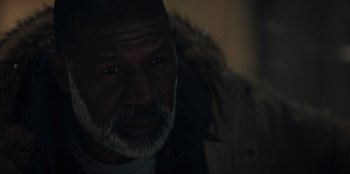 Movie still from “No Exit” (2022), directed by Damien Power – An older man with a beard and a jacket on; Close Up shot, Low angle