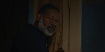 Movie still from “No Exit” (2022), directed by Damien Power – A man standing in front of a wooden door; Close Up shot, Low angle