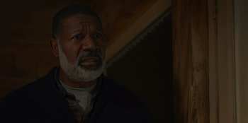 Movie still from “No Exit” (2022), directed by Damien Power – An older man with grey hair and a gray beard; Close Up shot, Over the shoulder angle