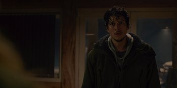 Movie still from “No Exit” (2022), directed by Damien Power – A man standing in a room with a window in the background; Close Up shot, Low angle