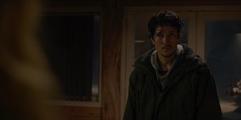 Movie still from “No Exit” (2022), directed by Damien Power – A man in a green jacket standing next to a door; Close Up shot, Low angle
