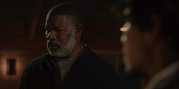 Movie still from “No Exit” (2022), directed by Damien Power – An older man with a gray beard is looking into the distance; Close Up shot, Over the shoulder angle