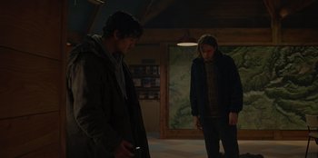 Movie still from “No Exit” (2022), directed by Damien Power – Two men are standing in a room looking at each other; Medium shot, Low angle