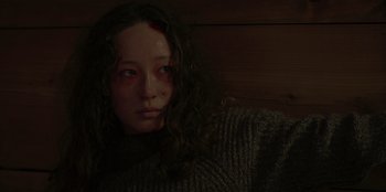 Movie still from “No Exit” (2022), directed by Damien Power – A young woman with long black hair wearing a gray sweater; Close Up shot, Low angle