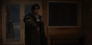 Movie still from “No Exit” (2022), directed by Damien Power – A man in a green jacket holding a camera; Medium shot, Over the shoulder angle
