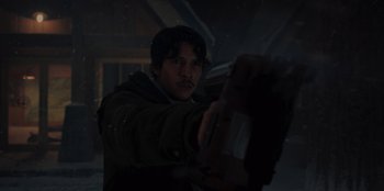 Movie still from “No Exit” (2022), directed by Damien Power – A man holding a gun in a dark room; Medium shot, Low angle