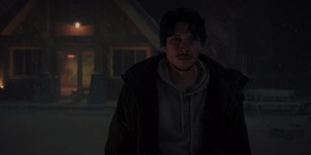Movie still from “No Exit” (2022), directed by Damien Power – A man in a hooded jacket standing in the dark; Medium shot, Over the shoulder angle