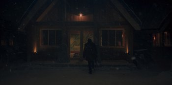 Movie still from “No Exit” (2022), directed by Damien Power – A person walking in the dark in front of a building; Extreme Wide shot, Low angle