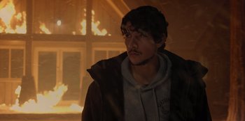 Movie still from “No Exit” (2022), directed by Damien Power – A man standing in front of a burning building; Close Up shot, Over the shoulder angle