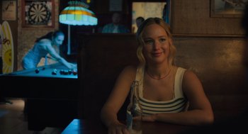 Movie still from “No Hard Feelings” (2023), directed by Gene Stupnitsky – A woman sitting at a table with a bottle of beer; Close Up shot, Over the shoulder angle
