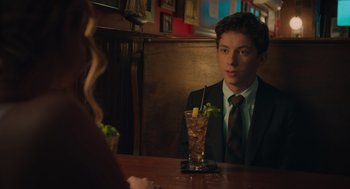 Movie still from “No Hard Feelings” (2023), directed by Gene Stupnitsky – A man and a woman sitting at a table with a drink; Medium shot, Over the shoulder angle