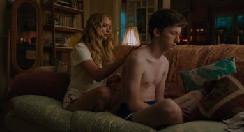 Movie still from “No Hard Feelings” (2023), directed by Gene Stupnitsky – A young man sitting on a couch next to a young woman; Medium shot, Over the shoulder angle