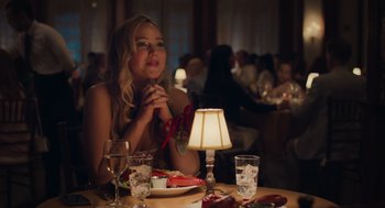 Movie still from “No Hard Feelings” (2023), directed by Gene Stupnitsky – A beautiful young lady sitting at a table with a plate of food; Medium shot, Over the shoulder angle