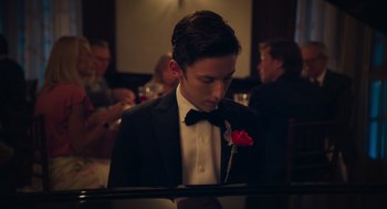 Movie still from “No Hard Feelings” (2023), directed by Gene Stupnitsky – A man in a tuxedo sitting at a piano with a rose in his mouth; Close Up shot, High angle