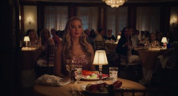 Movie still from “No Hard Feelings” (2023), directed by Gene Stupnitsky – A woman sitting at a table with a plate of food; Medium shot, Over the shoulder angle