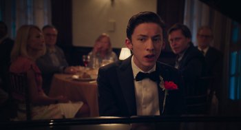 Movie still from “No Hard Feelings” (2023), directed by Gene Stupnitsky – A man in a tuxedo sitting in front of a piano in a restaurant; Close Up shot, Over the shoulder angle