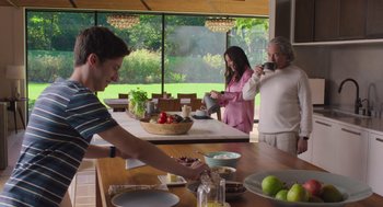 Movie still from “No Hard Feelings” (2023), directed by Gene Stupnitsky – A man and a woman standing in front of a table with food on it; Wide shot, Low angle