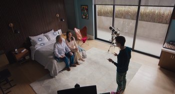 Movie still from “No Hard Feelings” (2023), directed by Gene Stupnitsky – A man standing in front of two women sitting on a bed; Wide shot, Overhead angle
