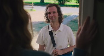 Movie still from “No Hard Feelings” (2023), directed by Gene Stupnitsky – A man with curly hair holding onto a black strap; Medium shot, Over the shoulder angle