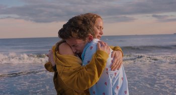 Movie still from “No Hard Feelings” (2023), directed by Gene Stupnitsky – A man and a woman hugging on the beach; Medium shot, Over the shoulder angle