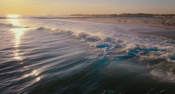 Movie still from “No Hard Feelings” (2023), directed by Gene Stupnitsky – The waves are crashing on the shore of the beach; Extreme Wide shot, High angle