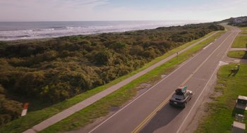 Movie still from “No Hard Feelings” (2023), directed by Gene Stupnitsky – A car driving down a road next to the ocean; Extreme Wide shot, High angle