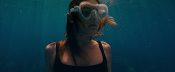 Movie still from “No Limit” (2022), directed by David M. Rosenthal – A woman wearing goggles in the water; Medium shot, High angle