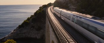 Movie still from “No Limit” (2022), directed by David M. Rosenthal – A train traveling on a train track next to the ocean; Extreme Wide shot, High angle