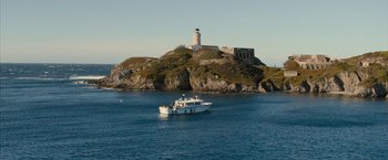 Movie still from “No Limit” (2022), directed by David M. Rosenthal – A boat in the water near a lighthouse; Extreme Wide shot, High angle