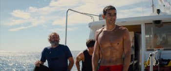 Movie still from “No Limit” (2022), directed by David M. Rosenthal – A man standing next to another man on a boat in the ocean; Medium shot, Over the shoulder angle