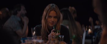 Movie still from “No Limit” (2022), directed by David M. Rosenthal – A woman sitting at a table with a bottle of beer; Close Up shot, Over the shoulder angle