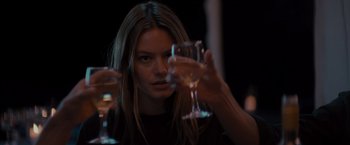 Movie still from “No Limit” (2022), directed by David M. Rosenthal – A woman holding a wine glass in front of her face; Close Up shot, Over the shoulder angle
