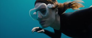 Movie still from “No Limit” (2022), directed by David M. Rosenthal – A woman wearing goggles swimming in the ocean; Close Up shot, High angle