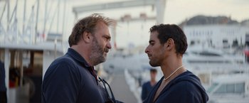 Movie still from “No Limit” (2022), directed by David M. Rosenthal – Two men talking to each other on a pier; Close Up shot, Over the shoulder angle