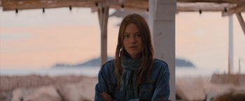 Movie still from “No Limit” (2022), directed by David M. Rosenthal – A woman with long hair wearing a denim jacket and a scarf; Close Up shot, Over the shoulder angle